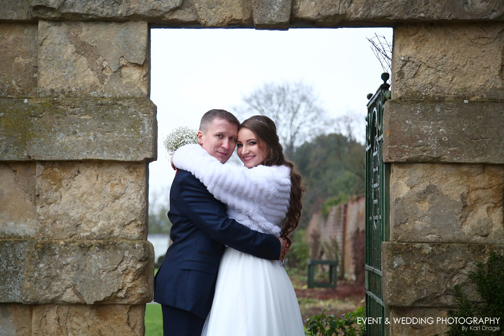 The bride and groom share an embrace in the gateway to the Walled Garden at Delapre Abbey on their wedding day.