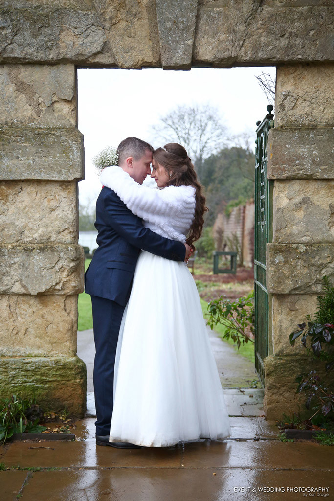 A tender moment between bride and groom in the gateway to the Walled Garden at Delapre Abbey, Northampton - by Northamptonshire wedding photographer Karl Drage