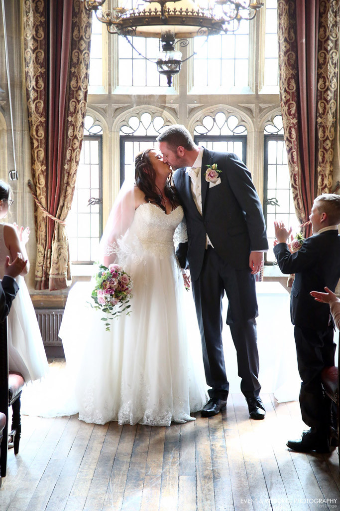 A loving kiss between husband and wife after a beautiful wedding ceremony in the stunning Baronial Hall at Highgate House, Creaton - by Northampton wedding photographer Karl Drage