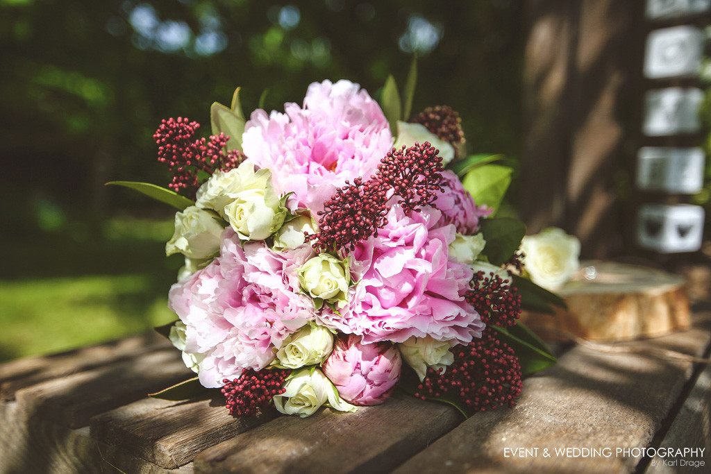 Hand-tied bridal bouquet of peony roses, skimmia and white spray roses by Rockingham Flowers