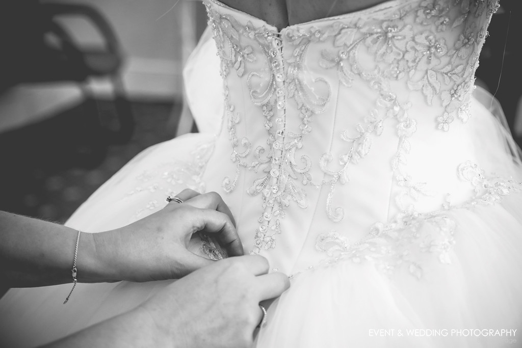 Buttoning up the bridal gown - by Northampton wedding photographer Karl Drage