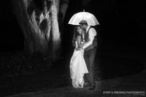 Image showing a husband and wife kissing under an umbrella in the rain.