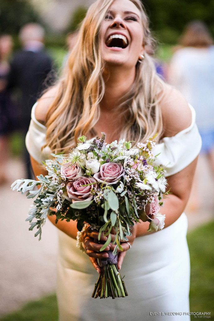 Bride laughing and holding her bridal bouquet at her Kelmarsh Hall wedding