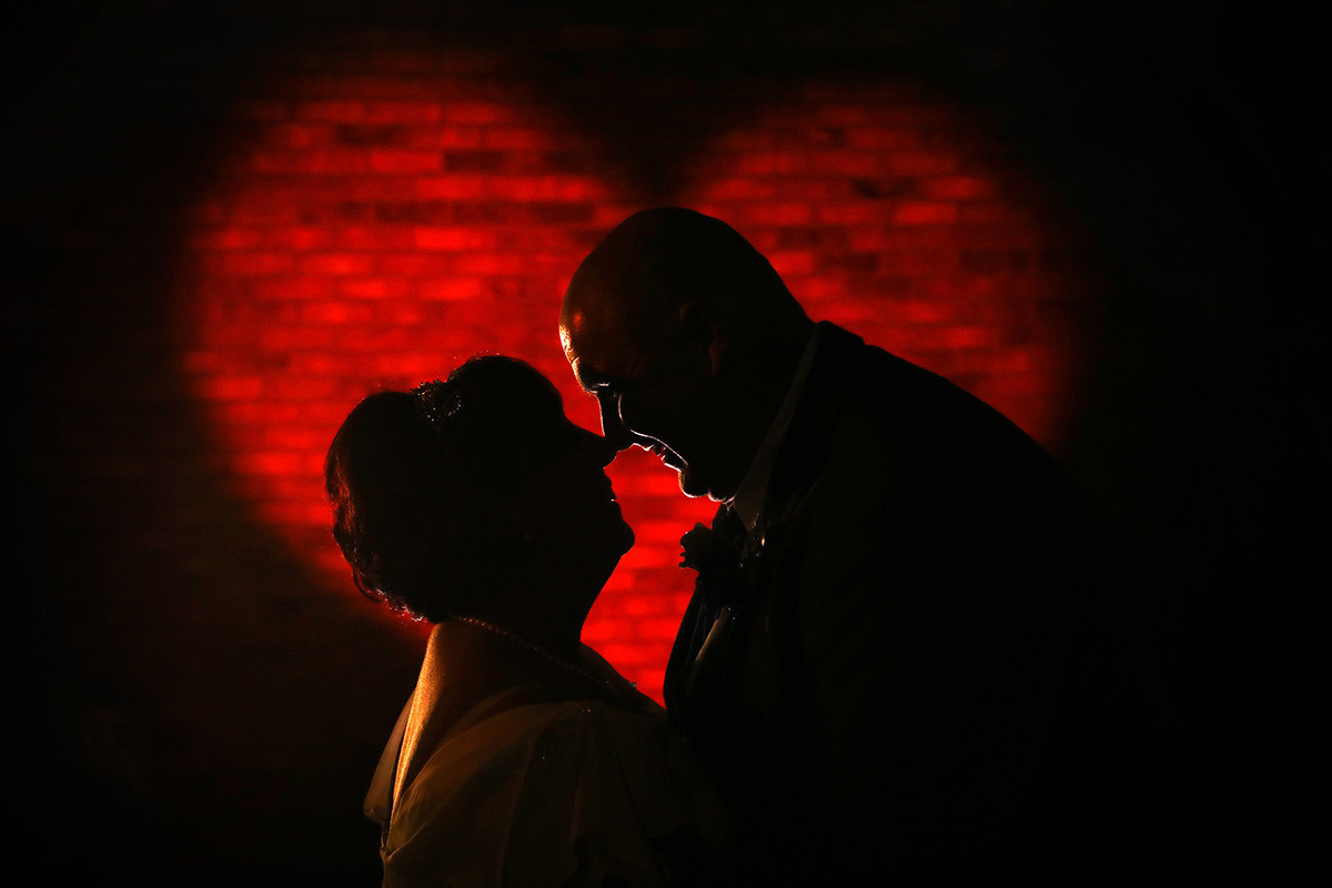Silhouetted bride and groom in front of an illuminated red heart