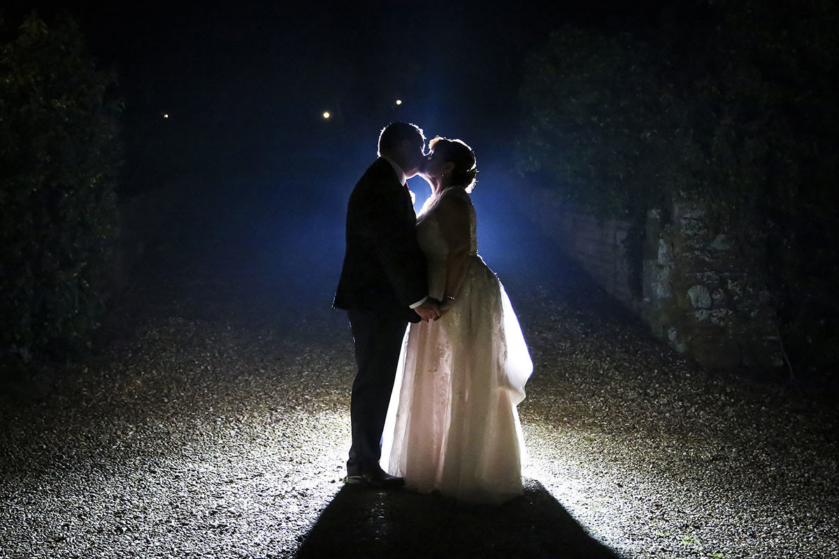Bride and groom kissing after dark.