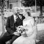 Bride and groom smiling on a swing at The Barns at Hunsbury Hill