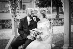 Bride and groom smiling on a swing at The Barns at Hunsbury Hill