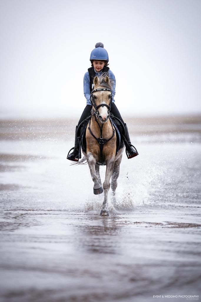 Pony splashes through the puddles on the beach