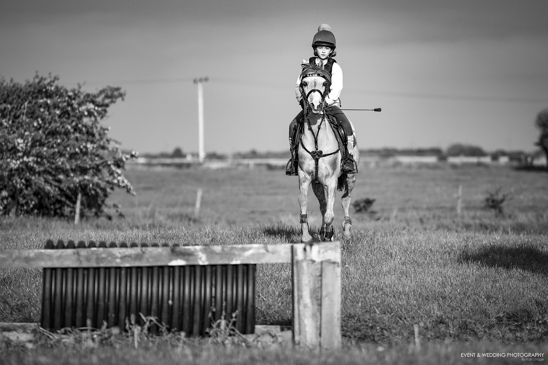 Black and white shot of horse and rider approachign a jump