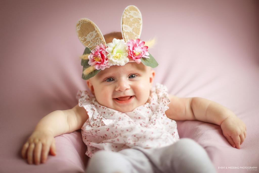 Baby wearing bunny ears sitting on a lilac blanket
