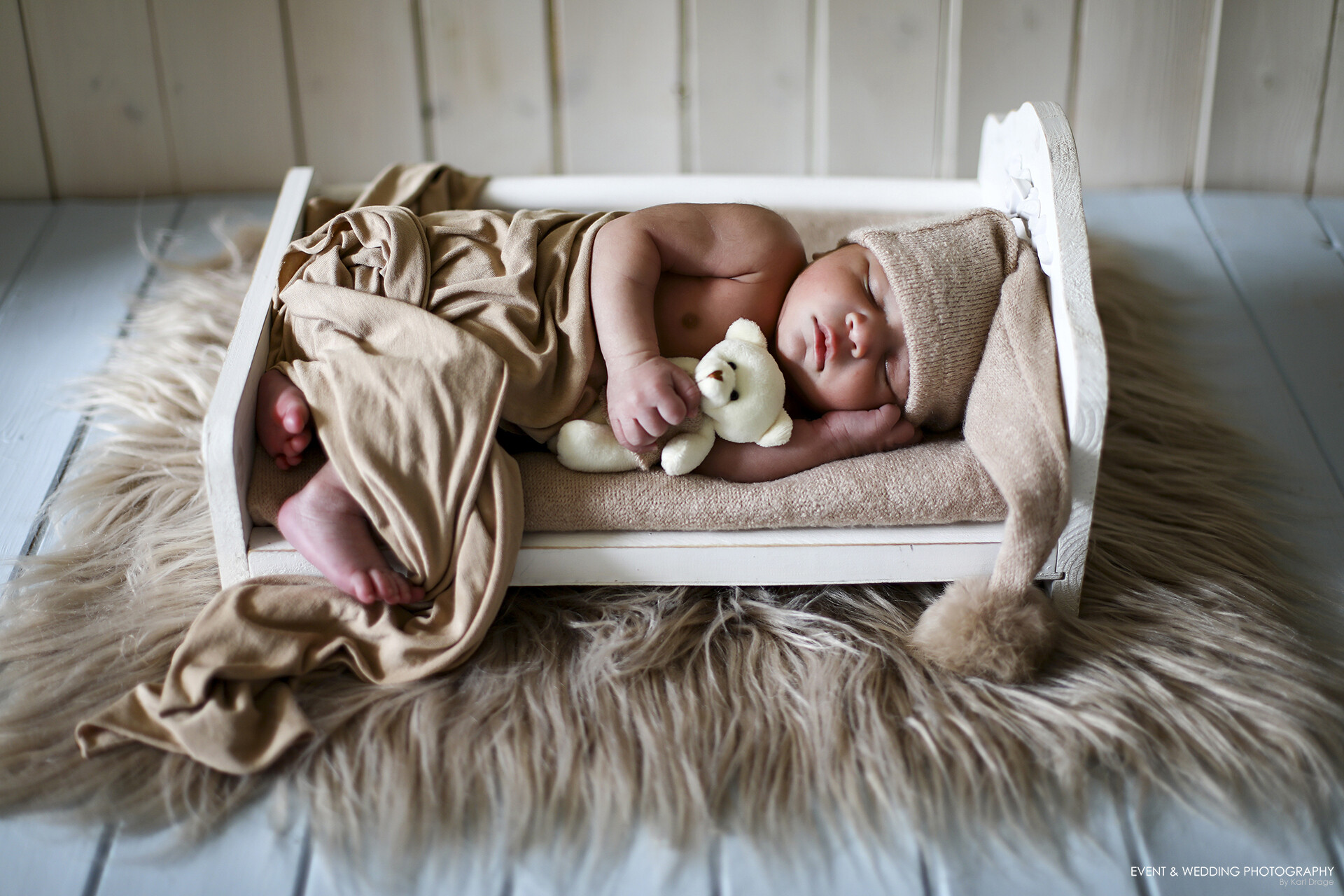 Newborn baby asleep on a wooden bed photo prop