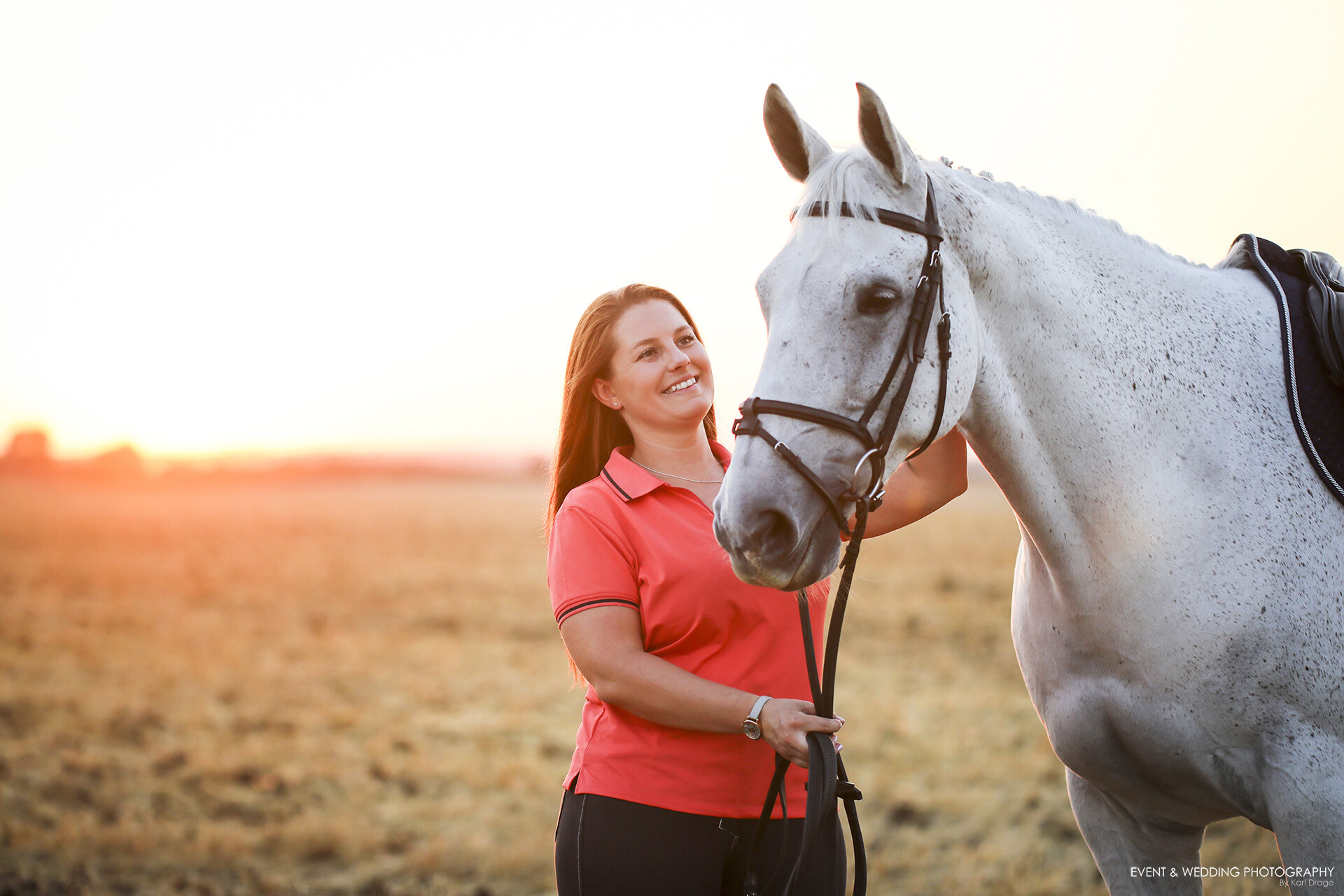 Backlit shot of a dismounted female rider patting her horse at sunset