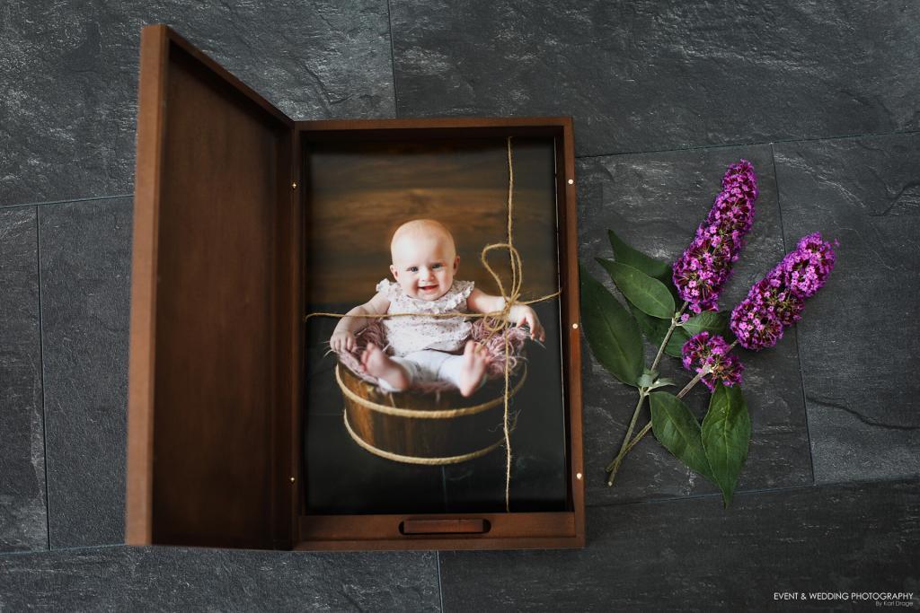 Photo of wooden presentation box containing a print of a baby sitting in a wooden bucket
