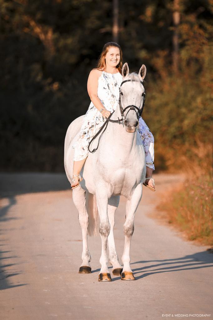 Portrait shot of a female rider in a dress on her grey horse