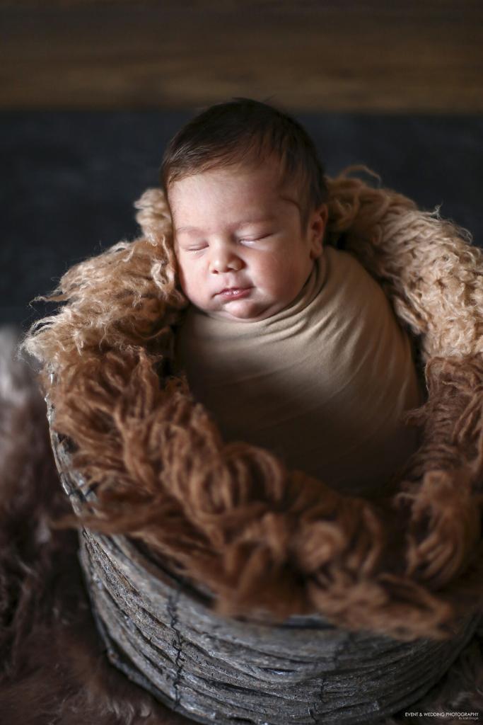 Newborn baby boy asleep in a tall wooden bowl photo prop