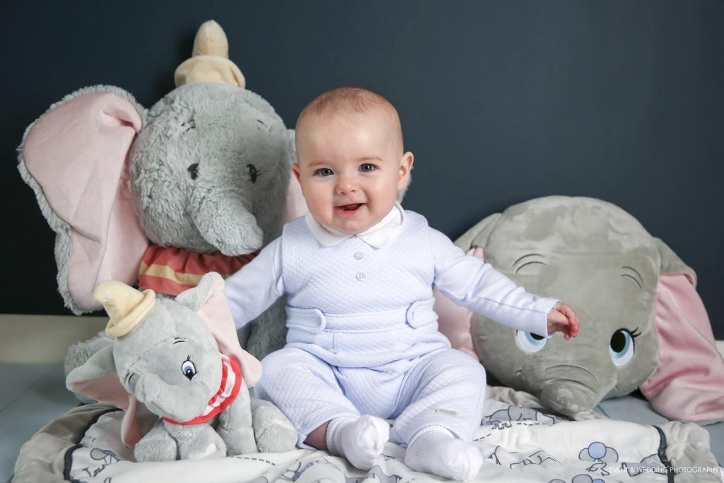Baby boy surrounded by elephant toys for his sitter photo session