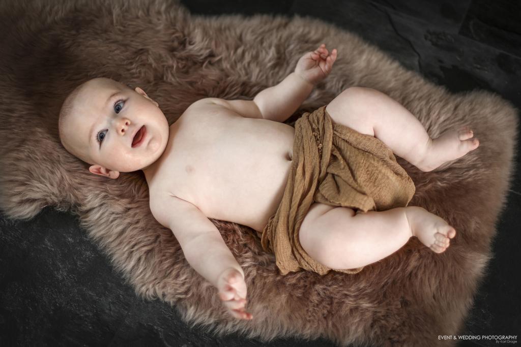 Baby boy laying on a brown sheepskin rug during a sitter photography session