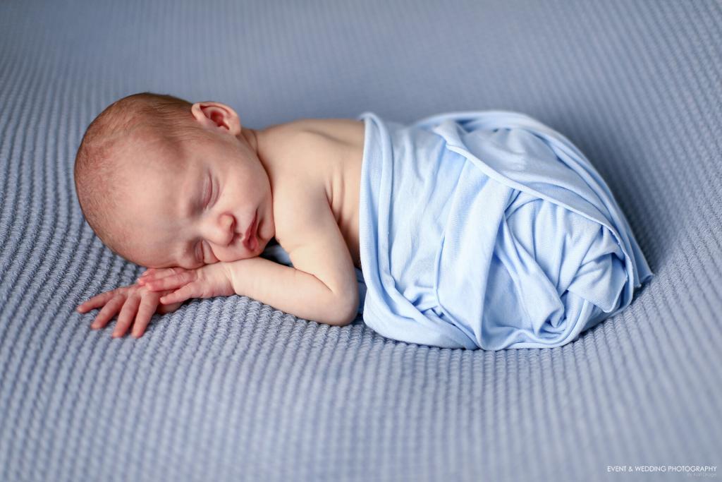 Newborn baby boy asleep on blue Berlin fabric blanket
