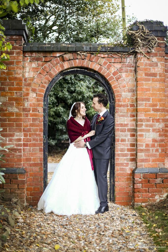 The Bride & Groom pose in an archway at Bredenbury Court Barns