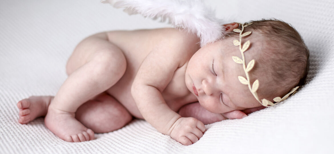 Newborn baby girl wearing angel wings