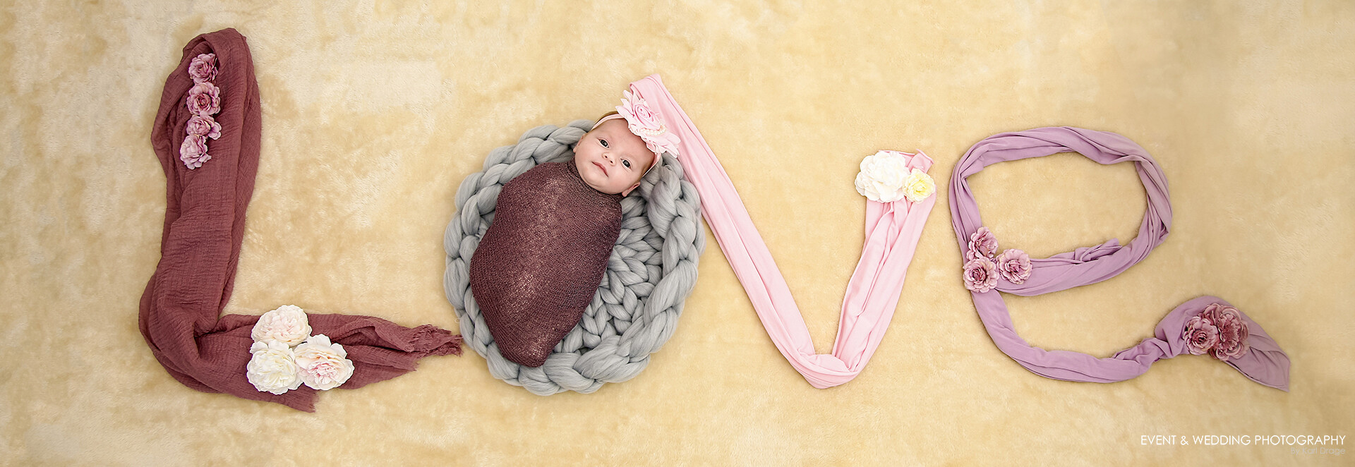 Newborn baby girl laying in a photography setup spelling the word Love in fabrics