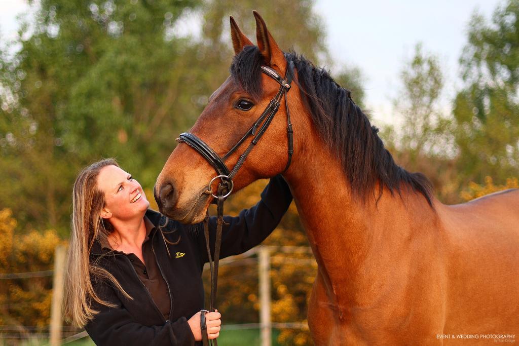 A lady gives her horse a reassuring pat on the neck