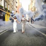 A bride and groom stride out down the middle of a road with smoke bombs after their Central London wedding