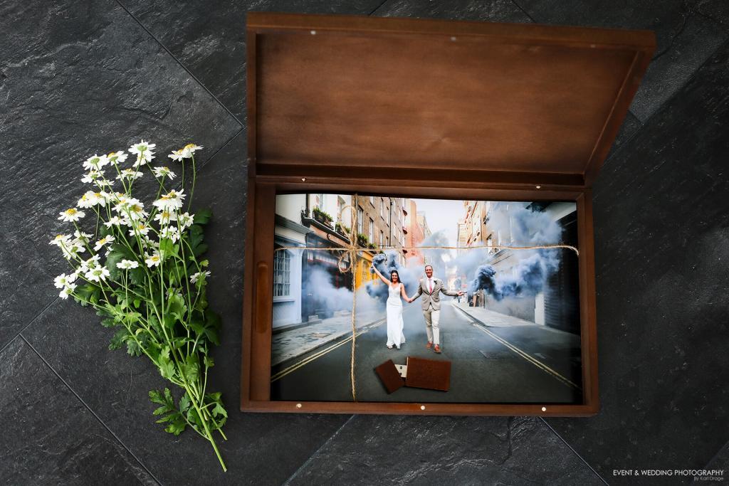 A large wooden presentation box containing prints of a bride and groom on their wedding day