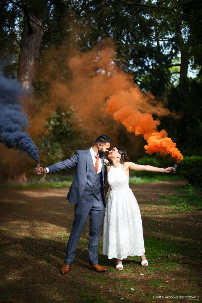 Bride and groom with black and orange smoke grenades on their wedding day