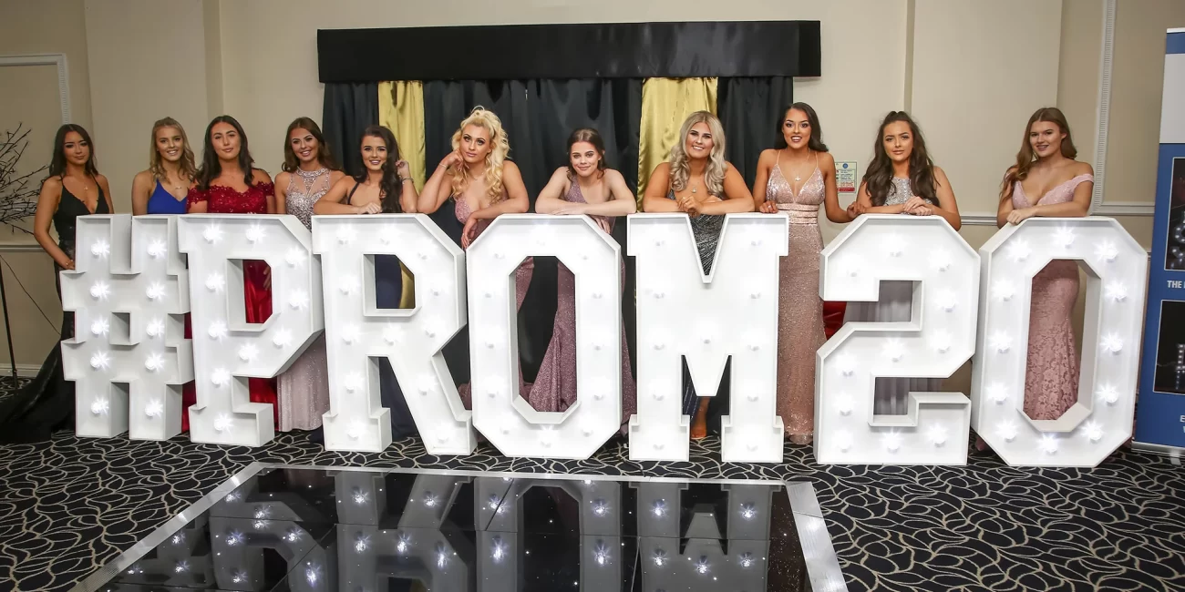 Models stand in front of #PROM20 illuminated letters