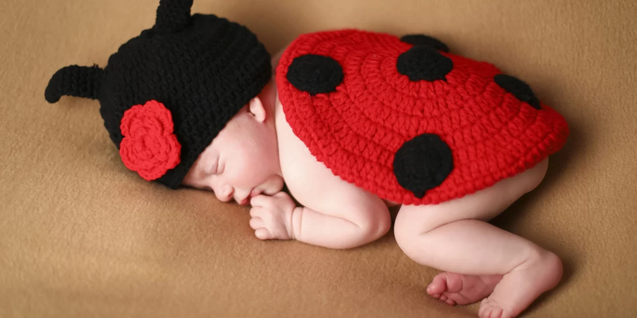 Baby girl wearing a woollen ladybird outfit