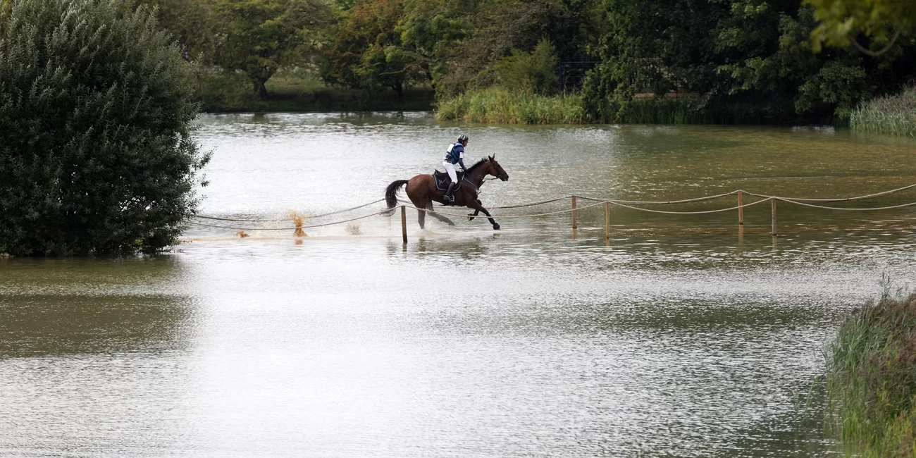 Cedric Lyard & Unum De'Or turn the corner splashing through the Boodles Raindance during the 2022 Burghley Horse Trials