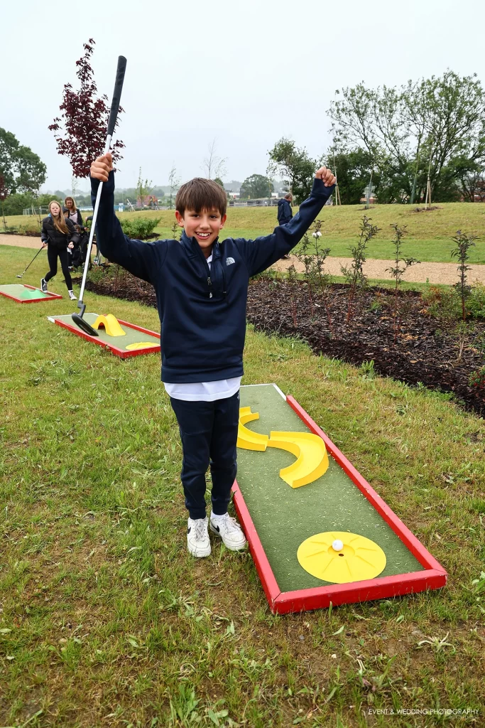 A boy celebrates sinking a putt on a crazy golf course
