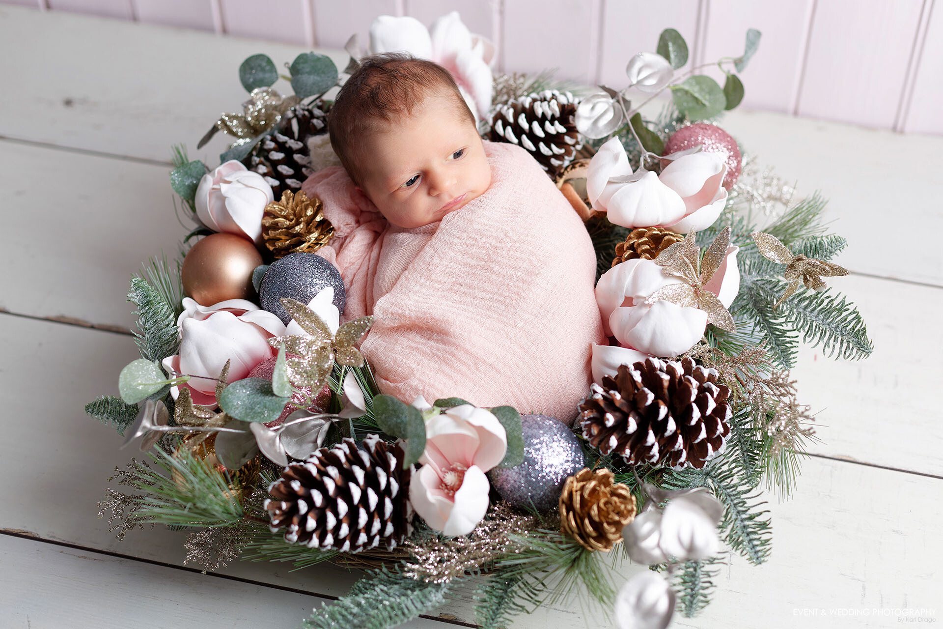A newborn baby girl posed in a Christmas wreath as part of her baby photo shoot.