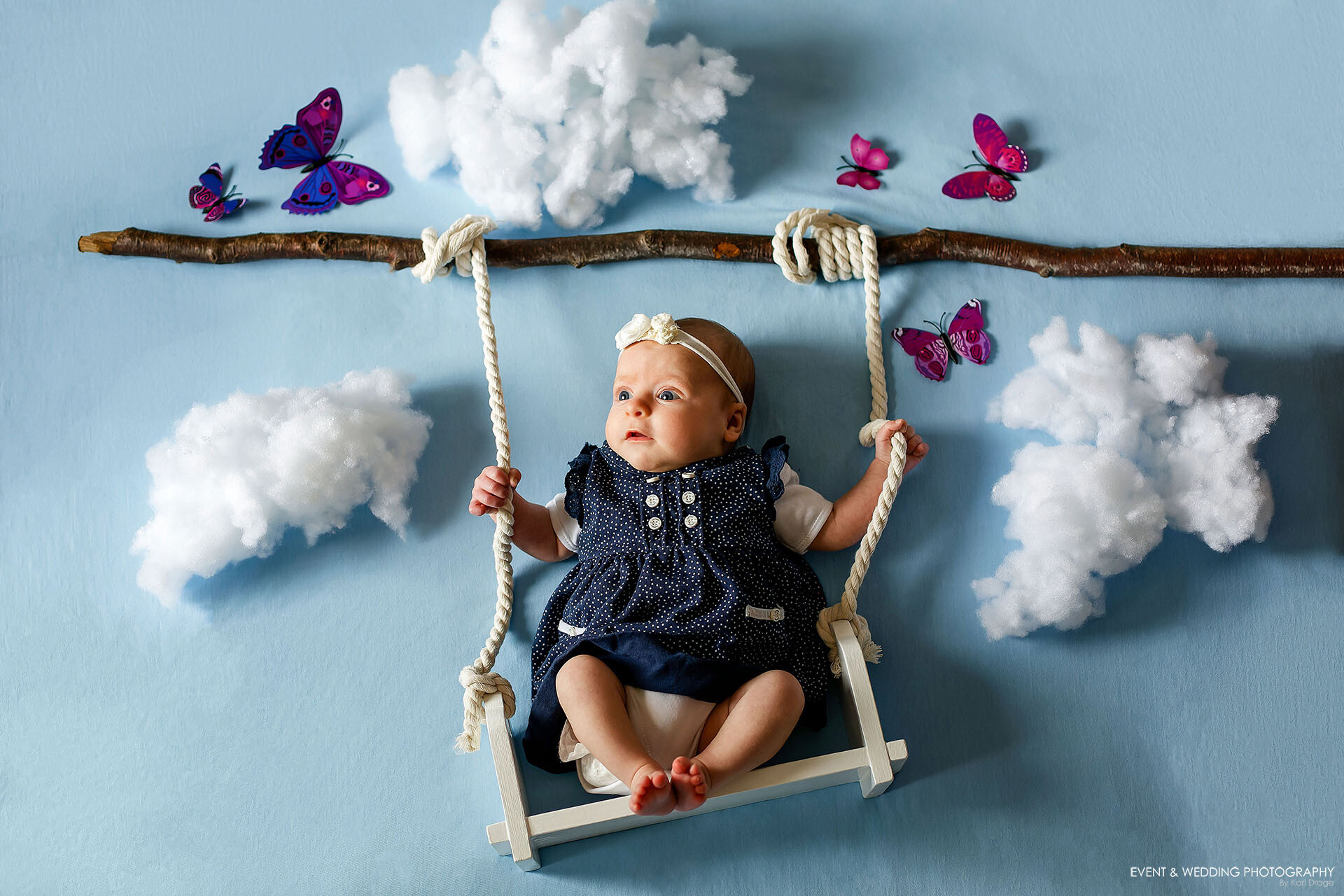 Baby Piper swings among the clouds and butterflies during her newborn photo shoot