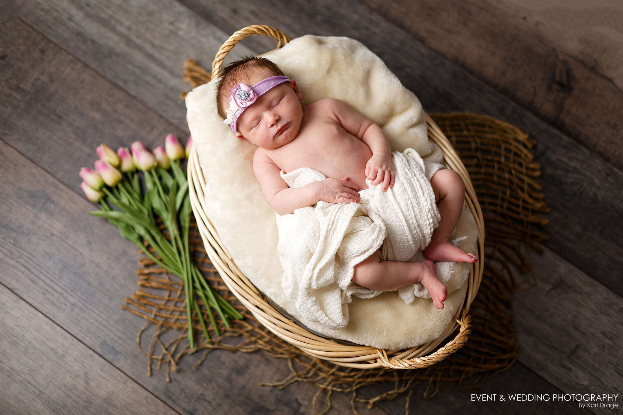 Baby girl asleep in a whicker basket during her newborn photo shoot near Corby.