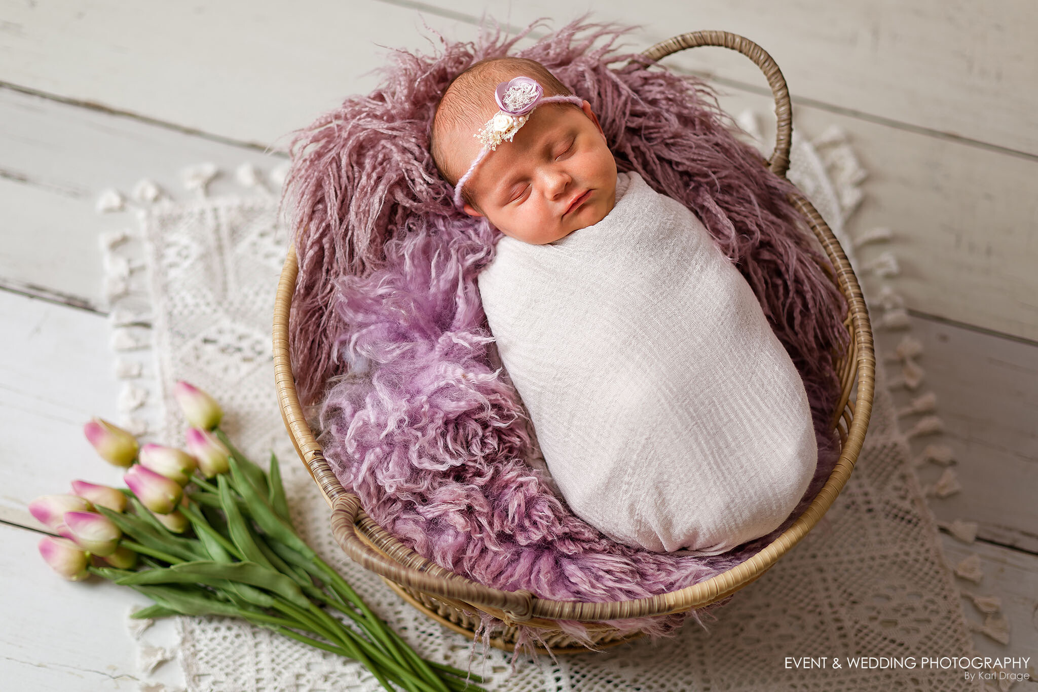 A baby girl sleeps in a rattan basket during her Wellingborough newborn photo shoot.