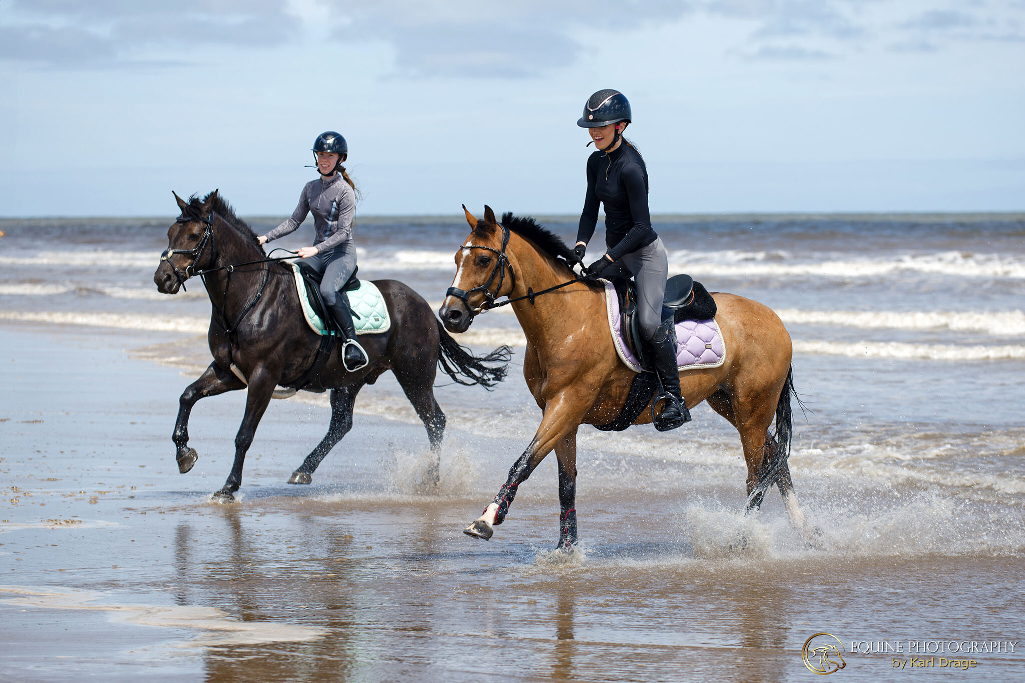 Two ladies ride their ponies out of the sea during a beach ride from Field Farm Equestrian Centre.