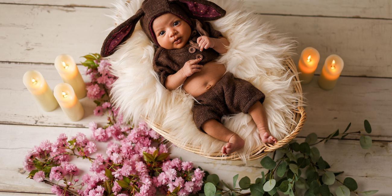 A newborn baby girl wearing the cutest bunny outfit lays on a fluffy blanket in a whicker basket during her Wellingborough Newborn Baby Photo Shoot.